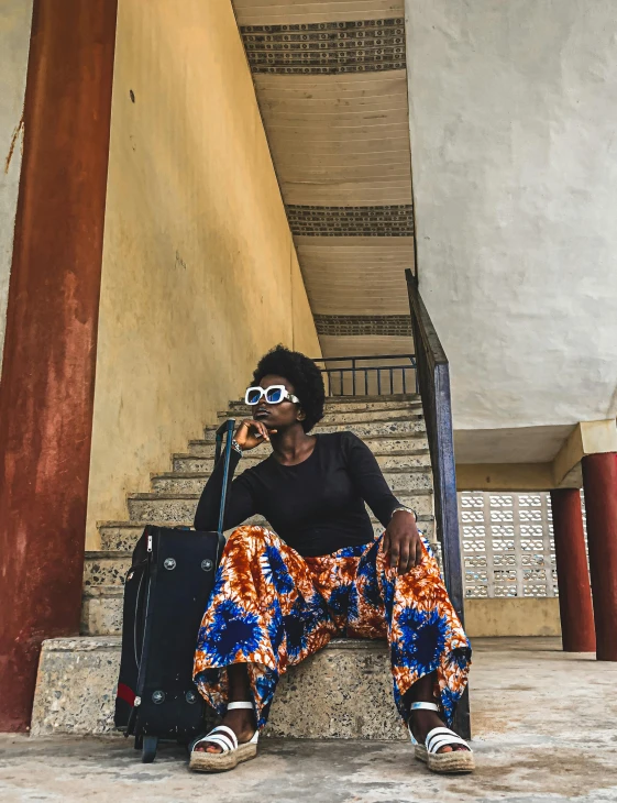 a person sitting on the stairs holding a suitcase and taking a po