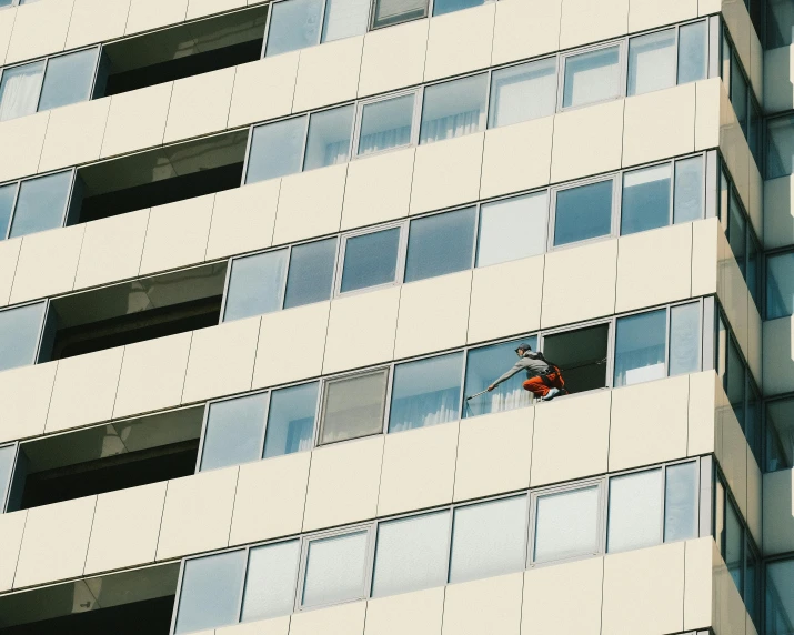 a person standing on the side of a window in a tall building