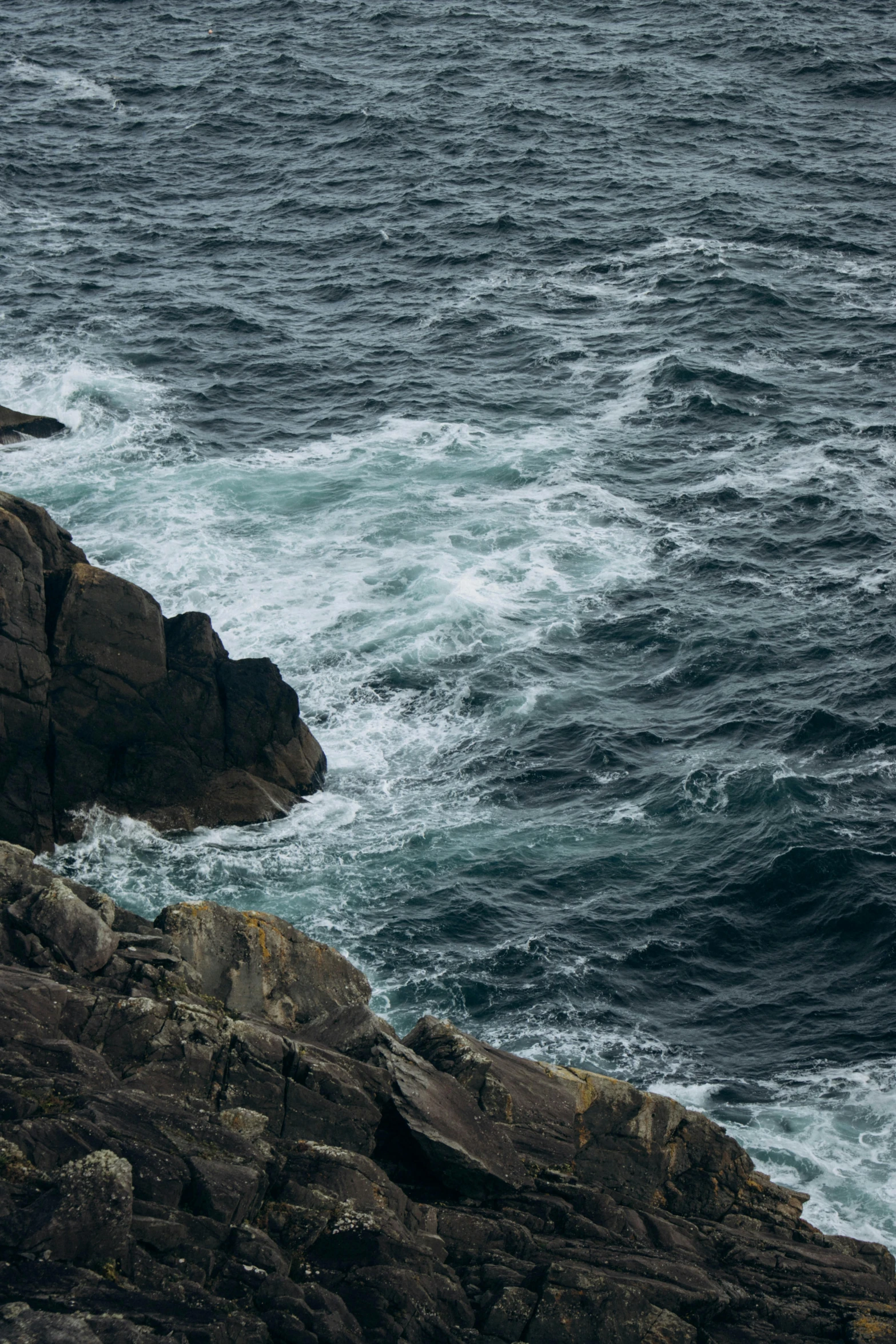 a person sitting on top of some rocks near the water