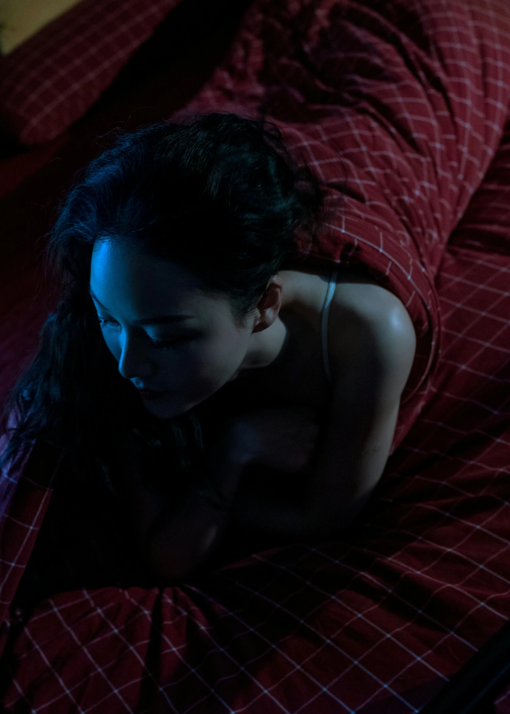 young woman looking down from bed on cell phone