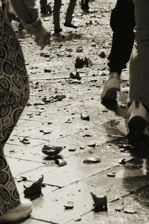 people walk on an over cast walkway with wet dles on the ground