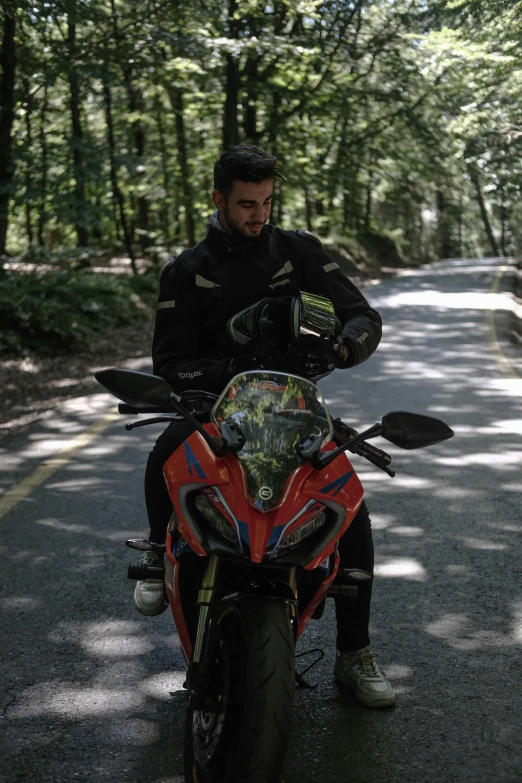 the man is sitting on a red motorcycle