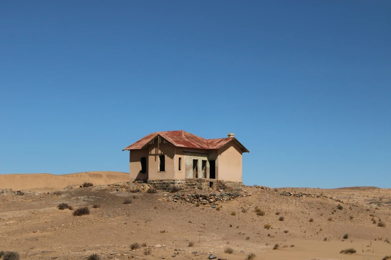 a building stands alone in the desert against a blue sky