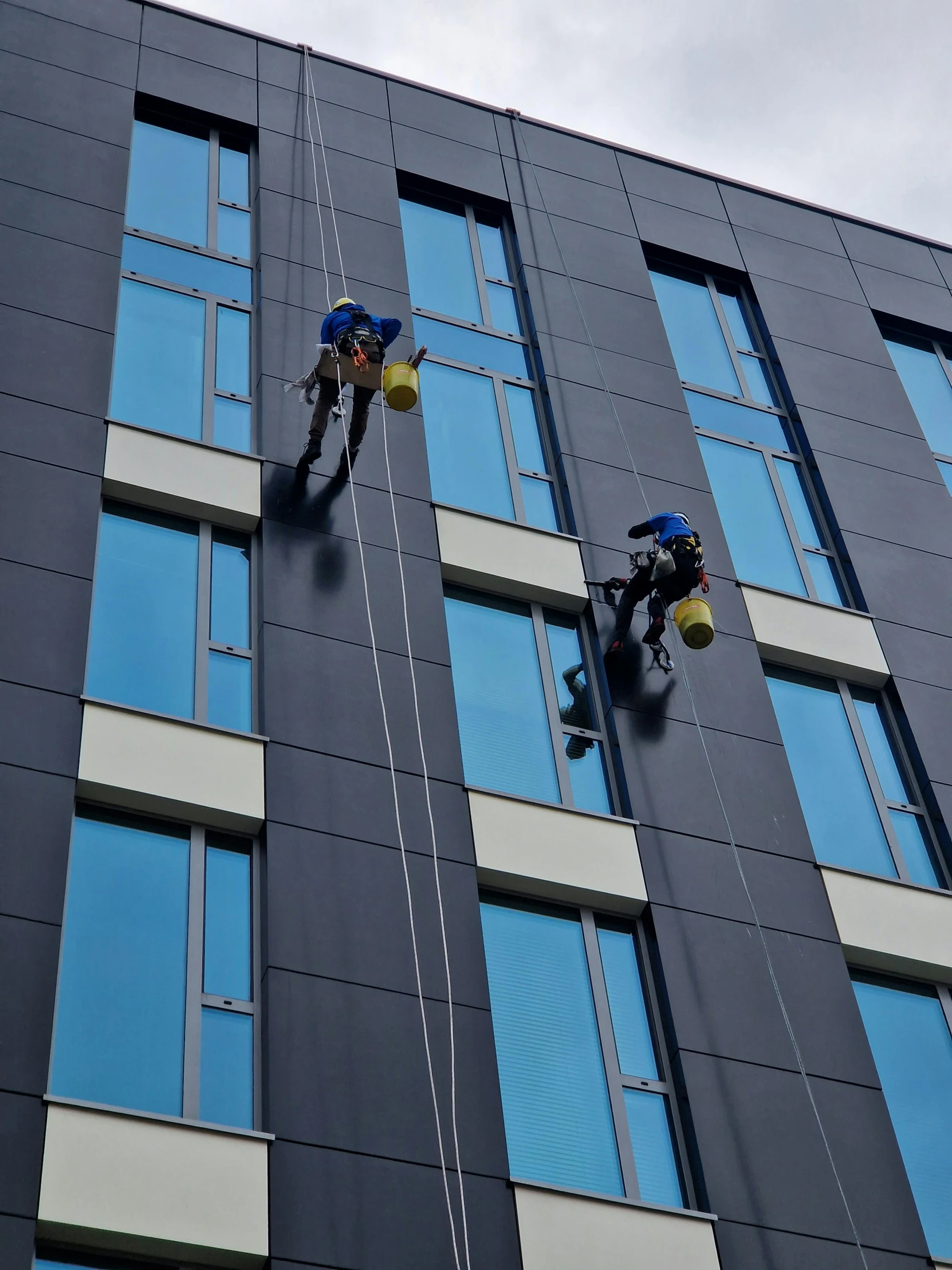 two workers are working on the side of a large building