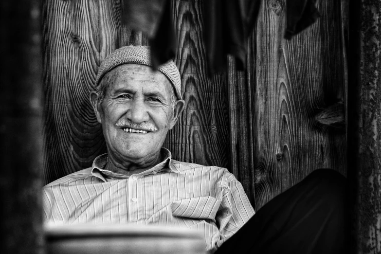 a man sitting next to a wooden building