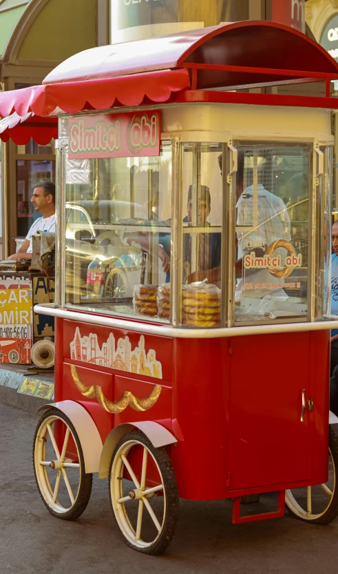 a woman and man behind a cart with lots of donuts on it