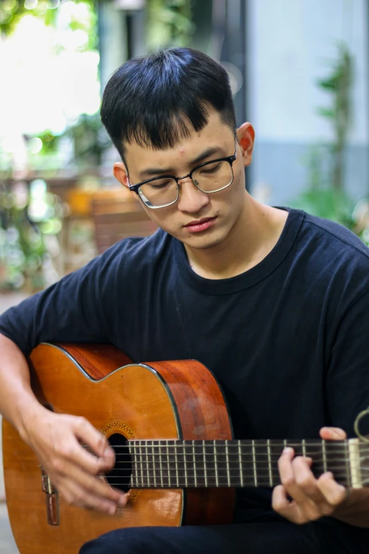 a young man is holding a guitar outside