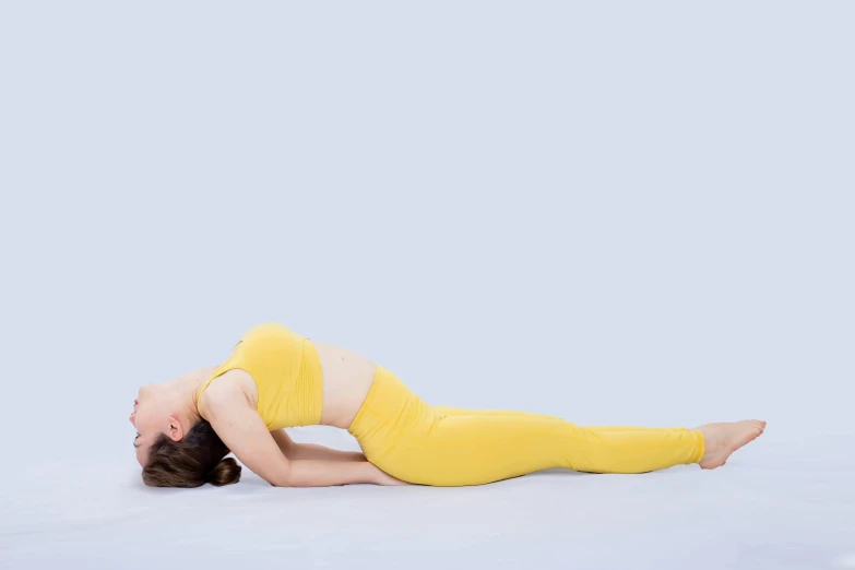 a woman in yellow on white doing yoga