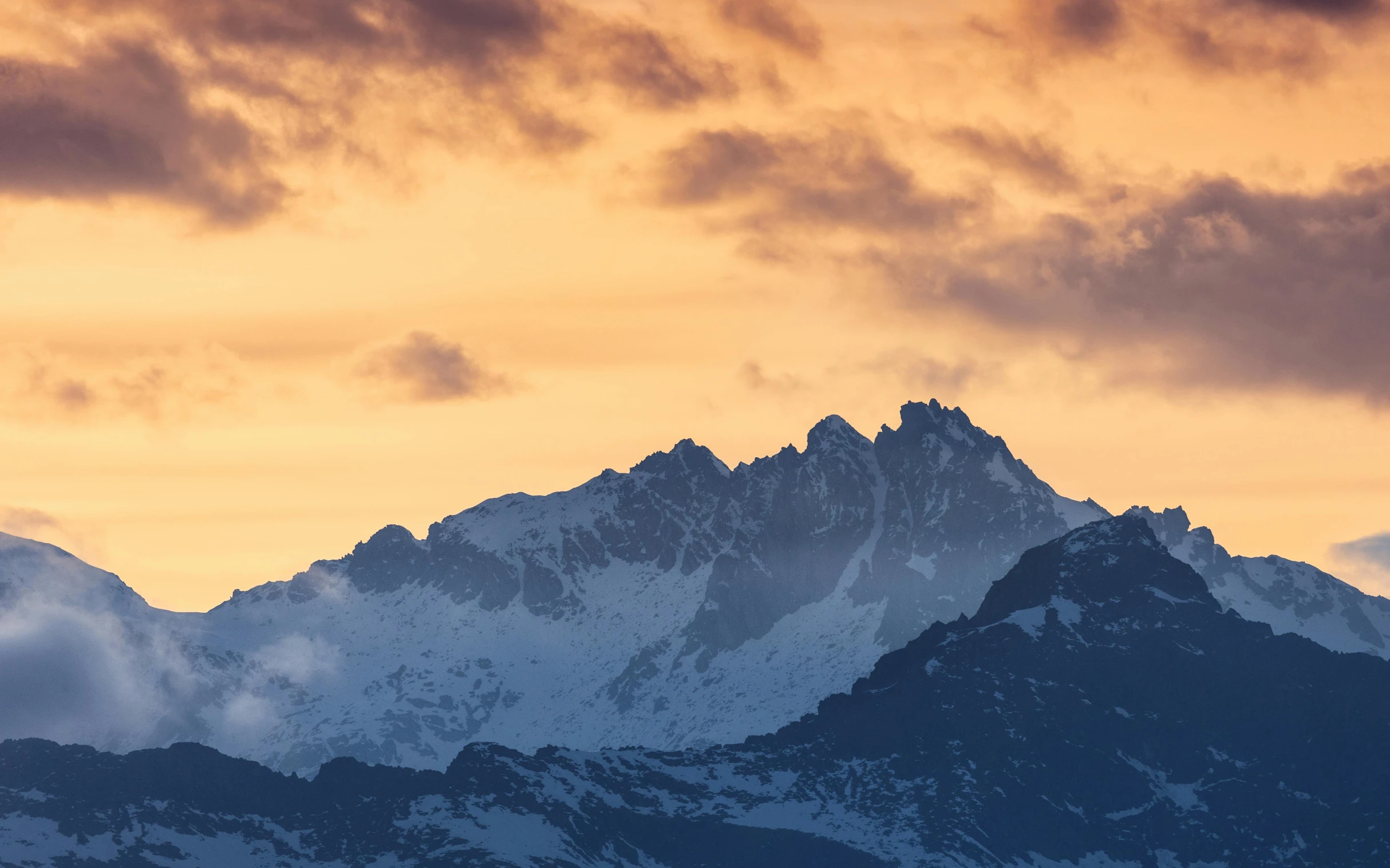 the mountains are covered with white clouds in the sunset