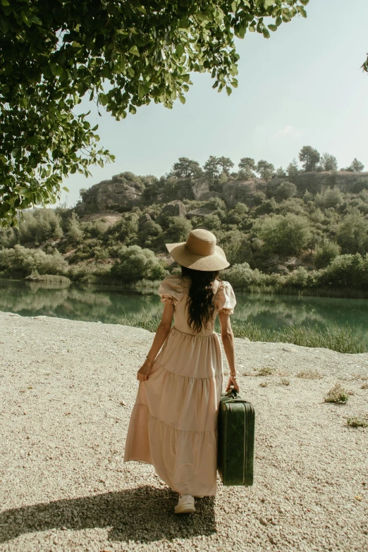 a woman in a hat walking away with a suitcase