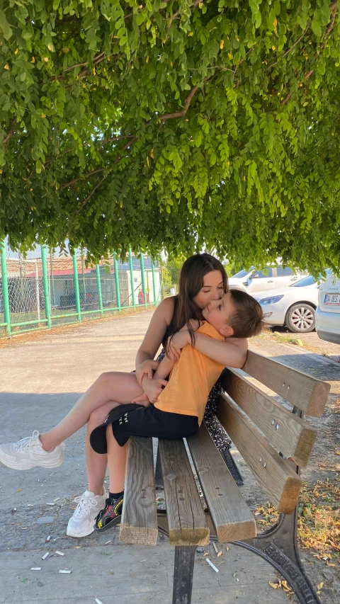 a mother and son kissing while sitting on a bench