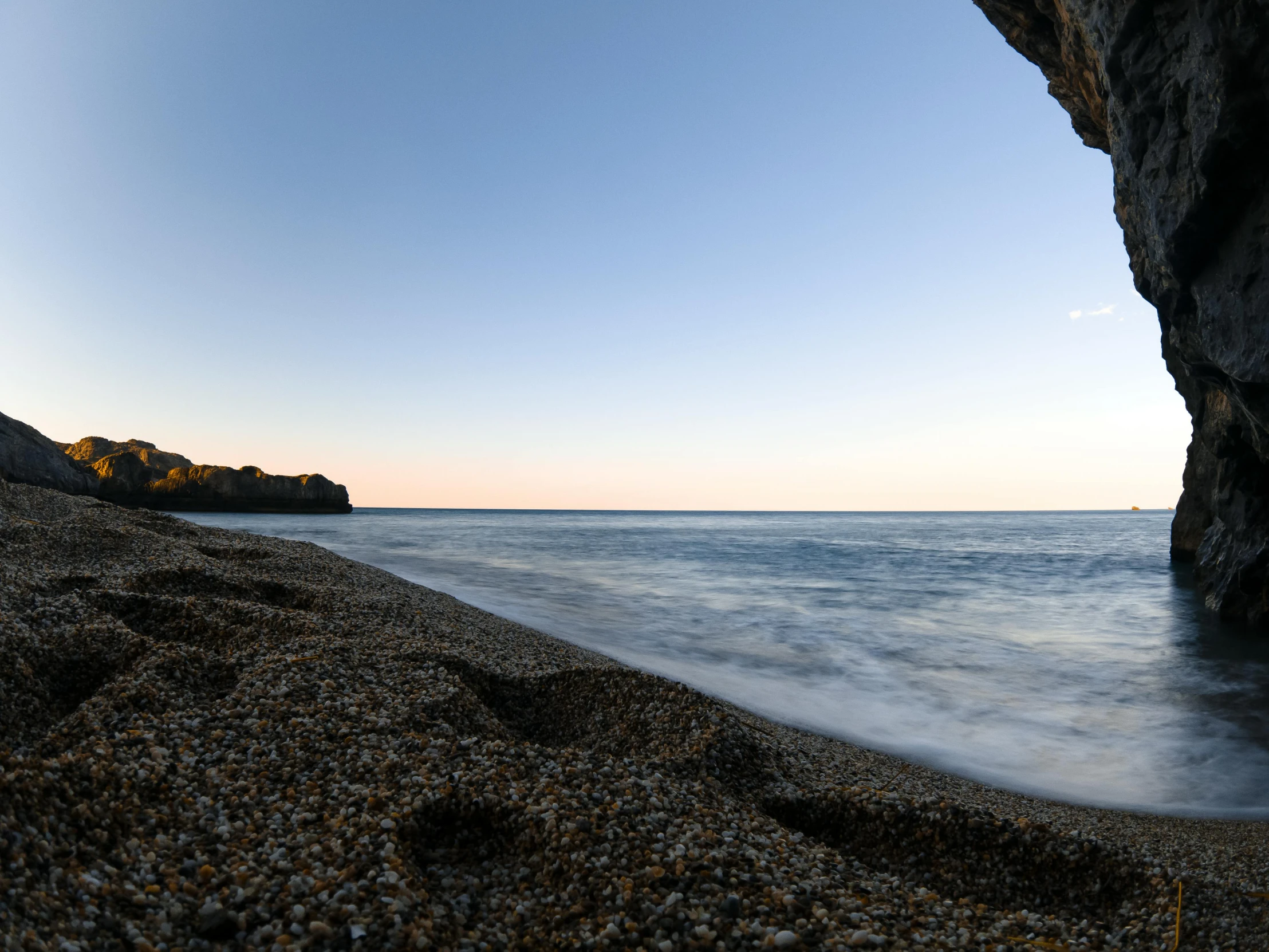 the beach is lined with pebbles and a little cliff