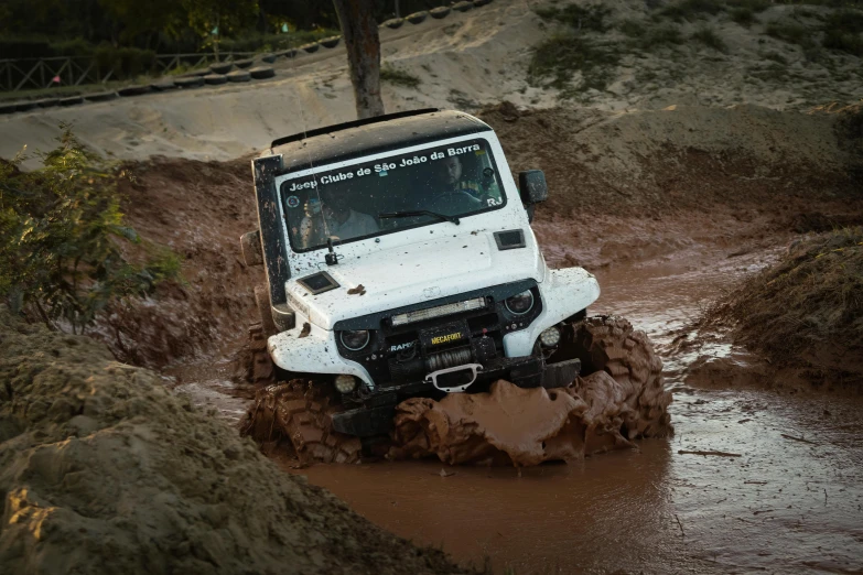 a white jeep driving through some muddy areas