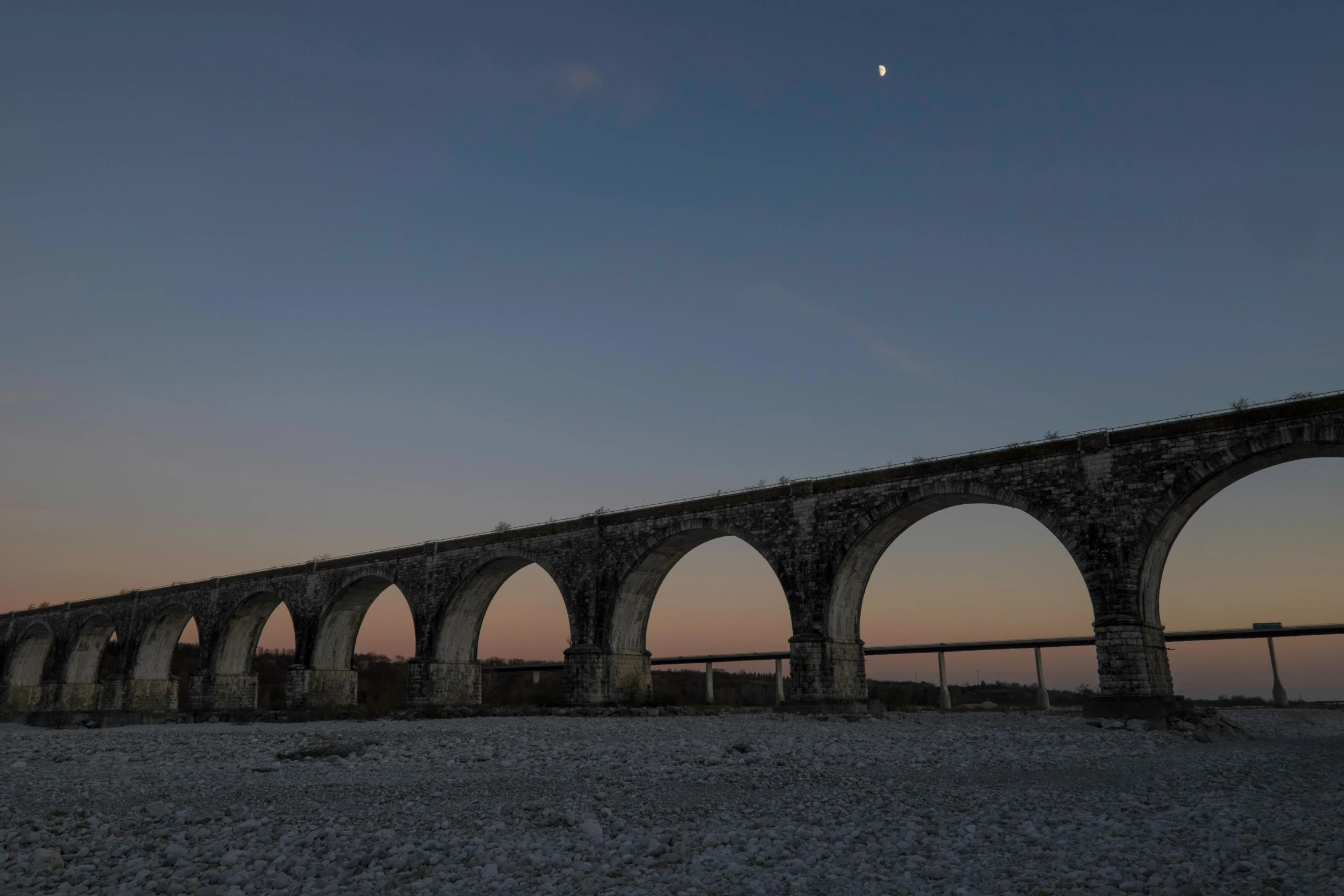 an ancient aqueduct bridge over the water at night