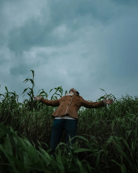 a woman standing in tall grass on top of a field