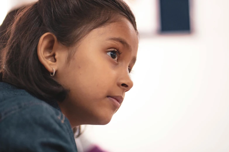 a little girl looking back while sitting on a chair