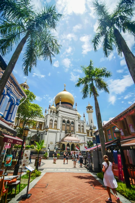 a white building with a yellow dome surrounded by palm trees