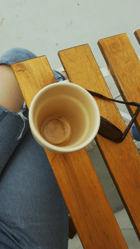 a person sitting on a bench with their legs crossed while holding onto the wooden seat