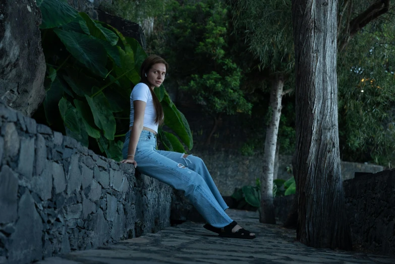 a woman leaning on a stone wall as she looks up