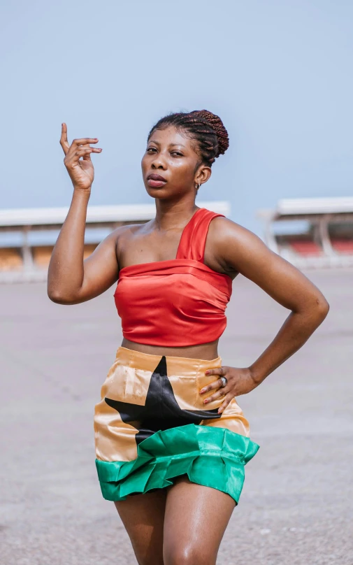 woman in a red top and green short skirt holding a peace sign