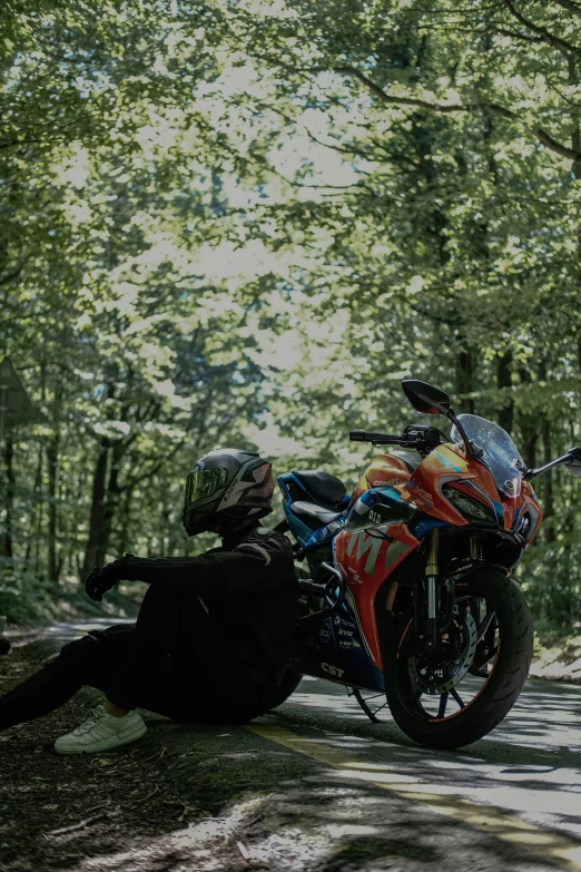 a person laying on the road next to a motorcycle