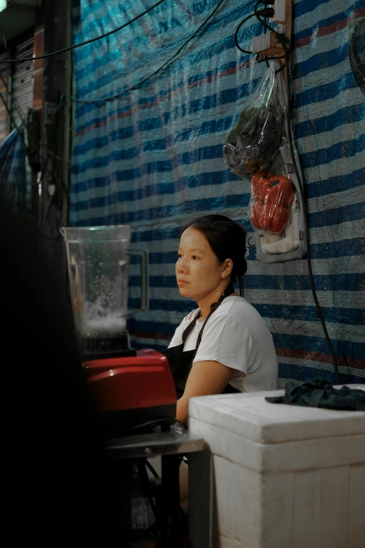 a woman is sitting behind an outside juicer