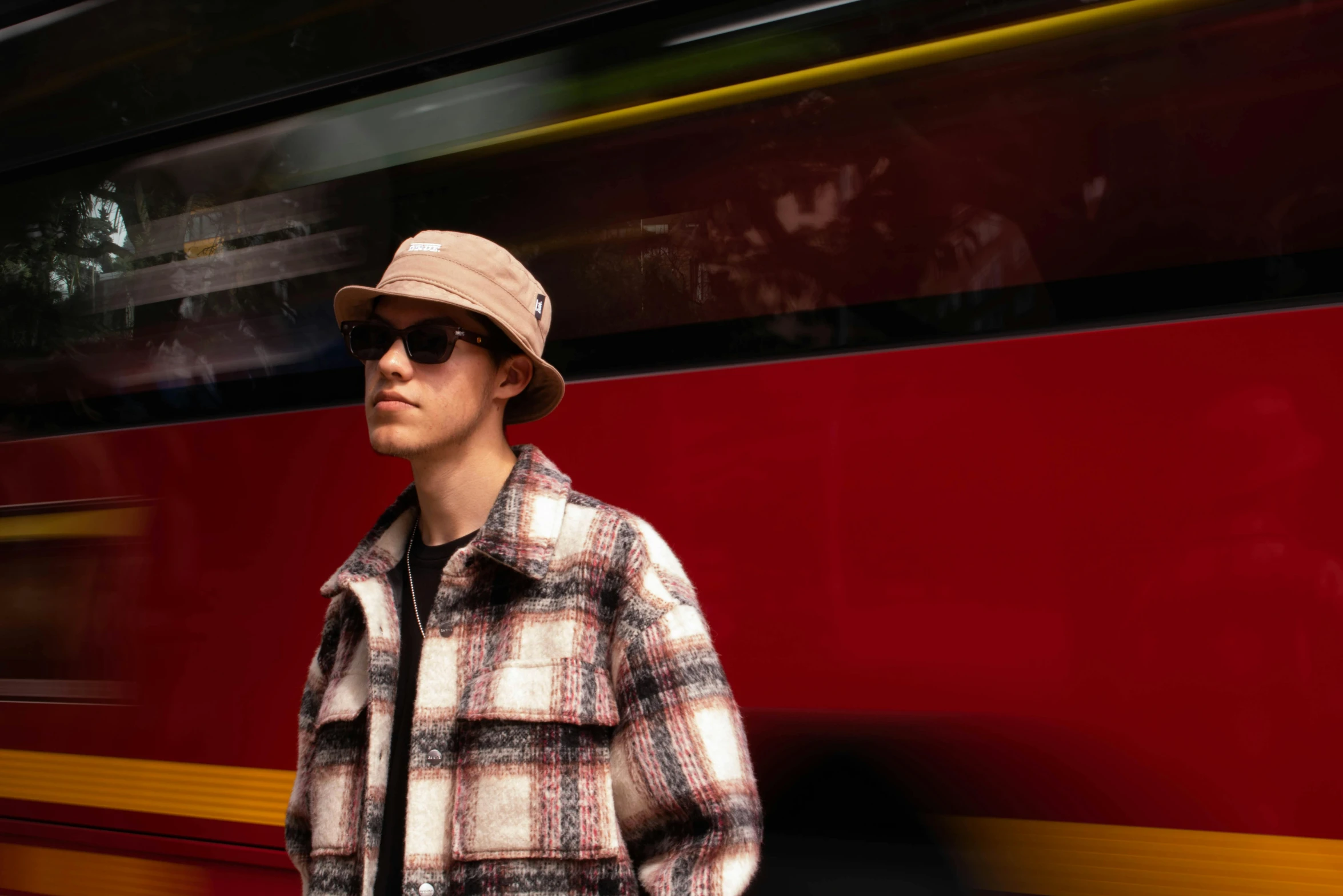 man wearing sunglasses and hat waiting at a bus stop
