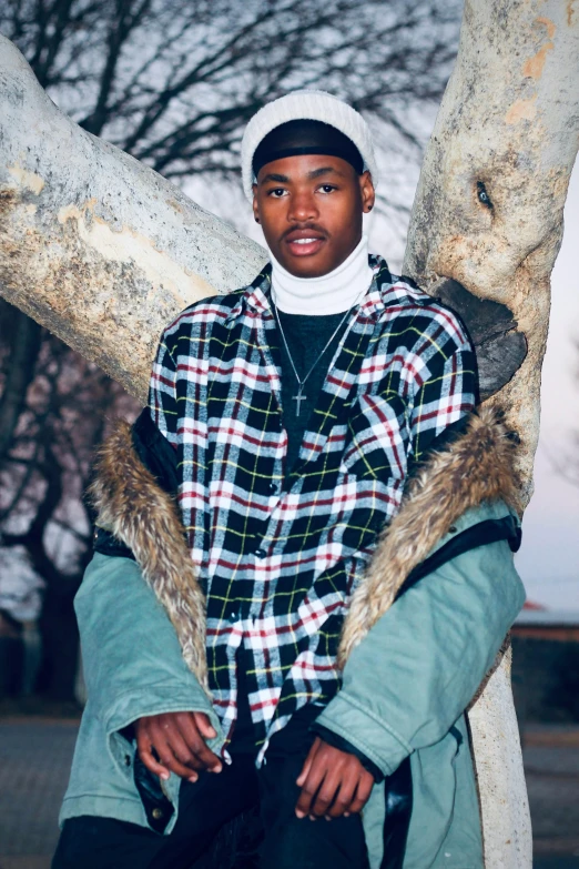 a black man is standing next to two trees