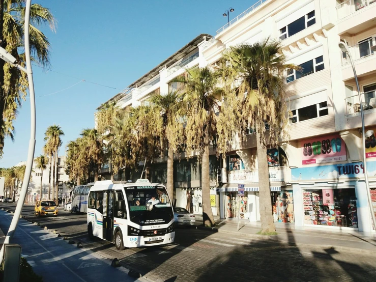 a white bus that is parked next to a tall building