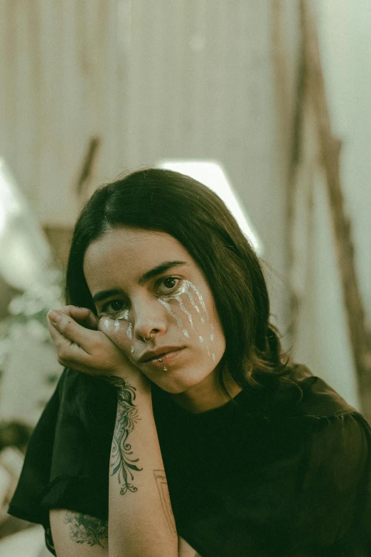 a young woman with tattoos on her arm sitting in a room