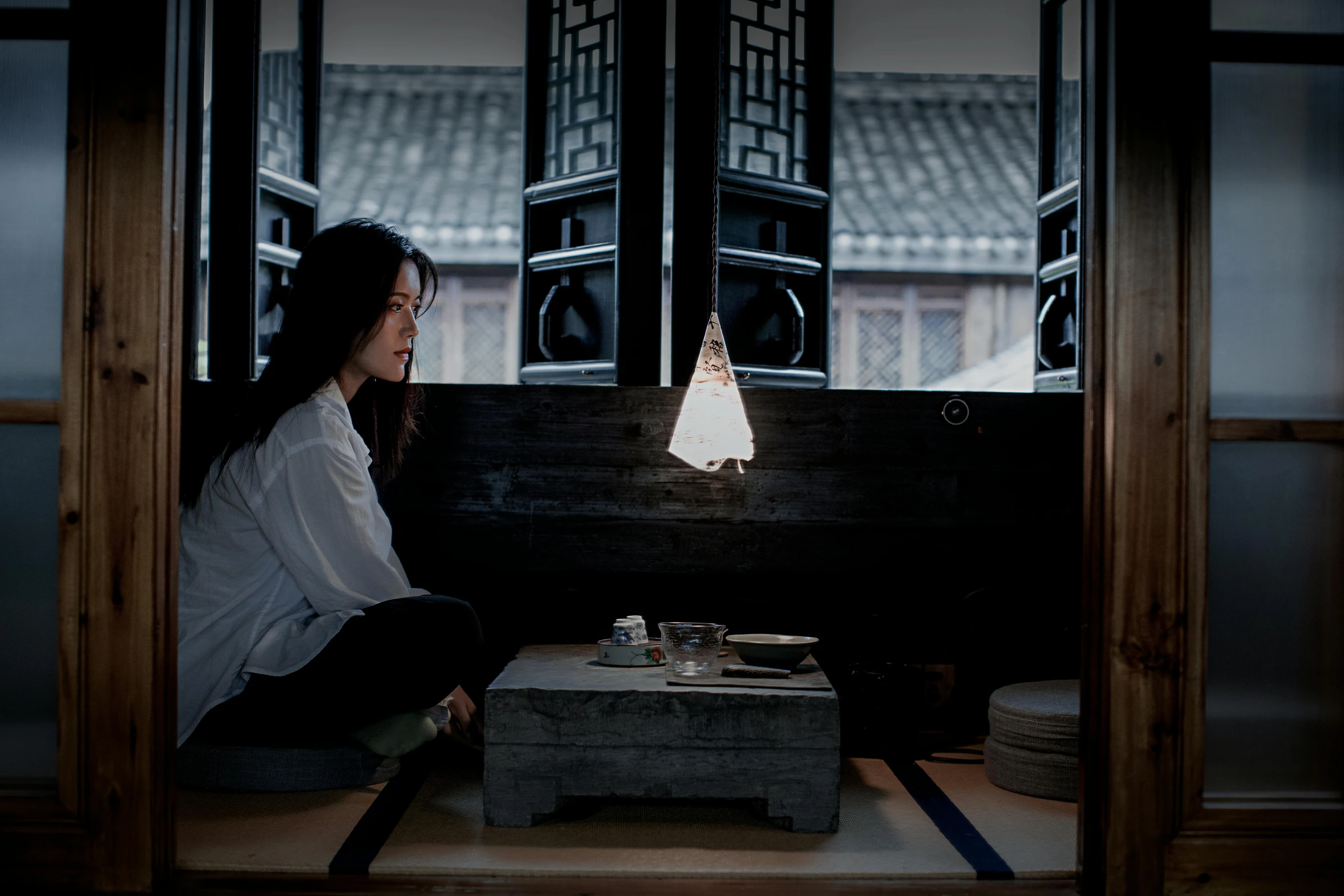 a woman sitting on a window sill looking out onto the street