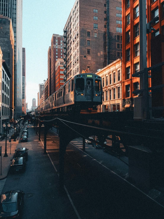 a train is crossing over a road and several tall buildings