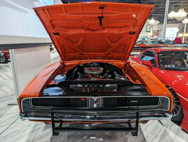 a red muscle car sits in a showroom with other vehicles