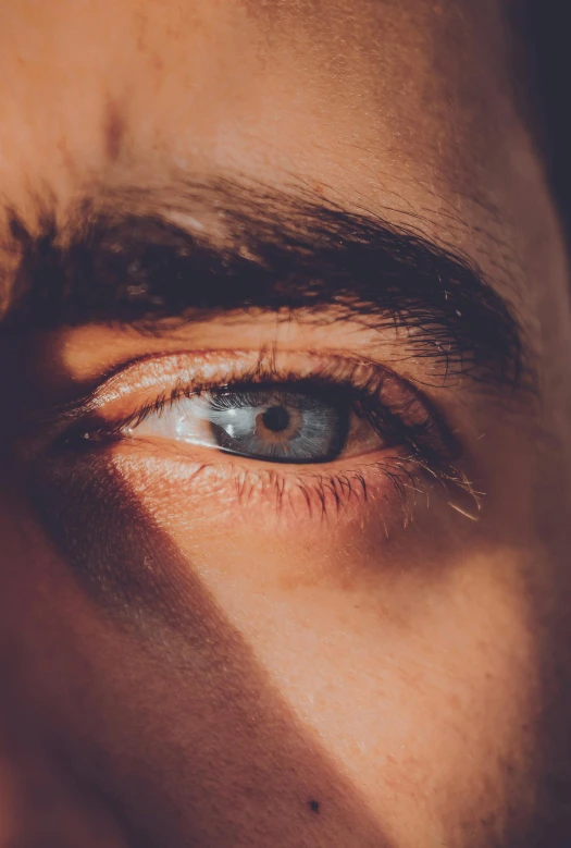 the blue - eyed man is holding a cell phone next to his eye