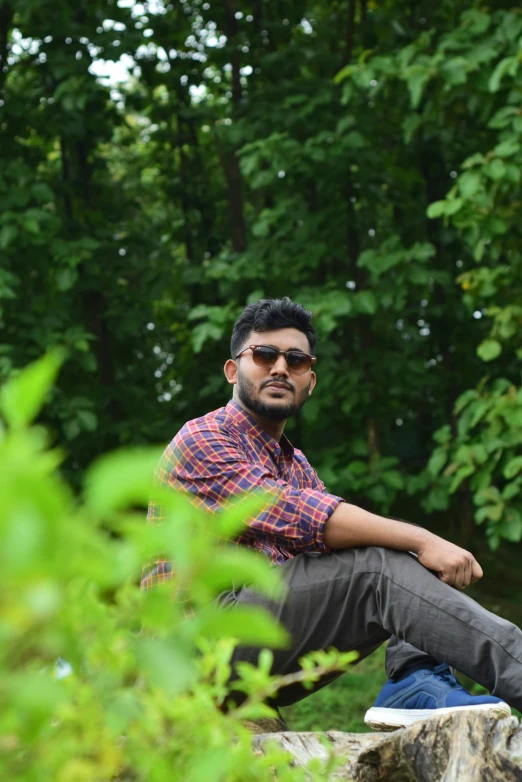 man sitting on top of a rock in a forest