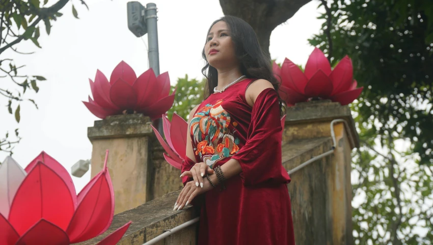 woman standing on a ledge next to red flowers