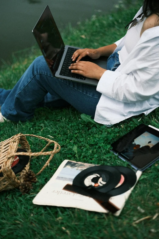 a person sitting in the grass on a laptop computer