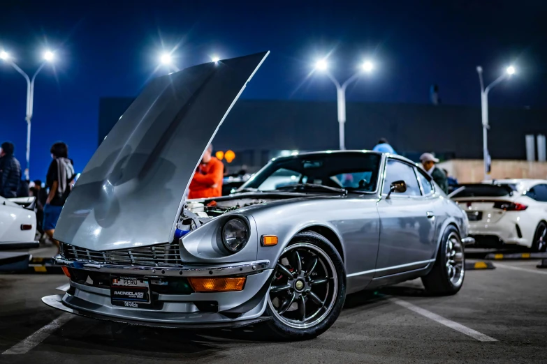 a silver car with its hood open on a parking lot