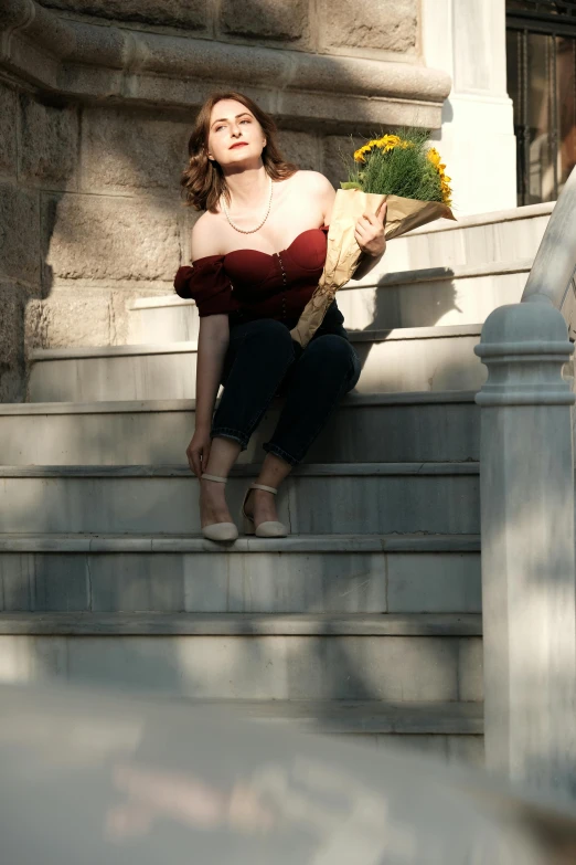 a woman sits on the steps holding flowers