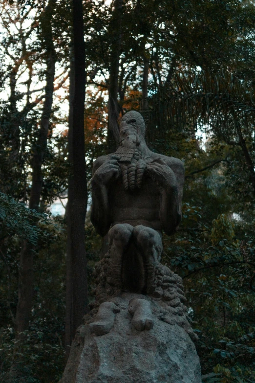 a statue sits between two trees in the woods