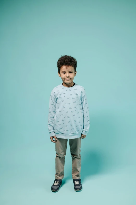 a little boy in a blue sweatshirt is standing and smiling