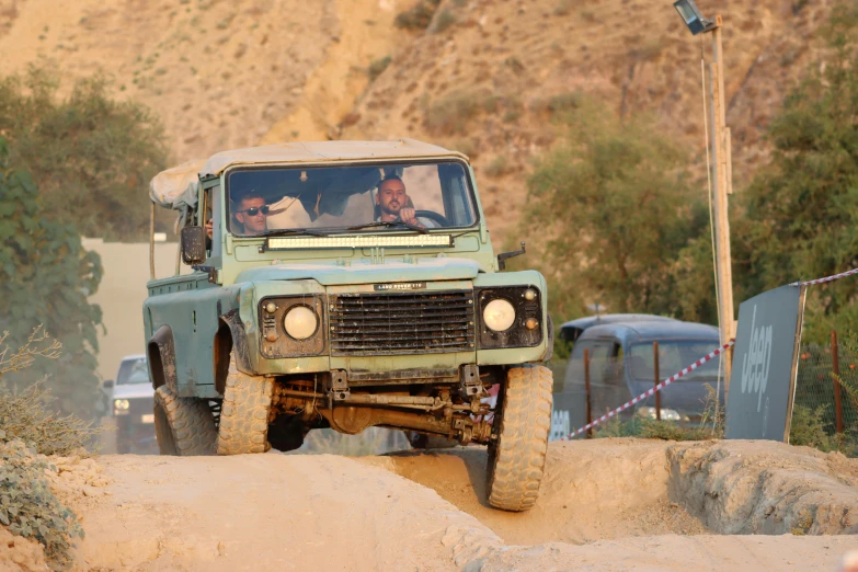 a dirty green truck driving down a dirt hill