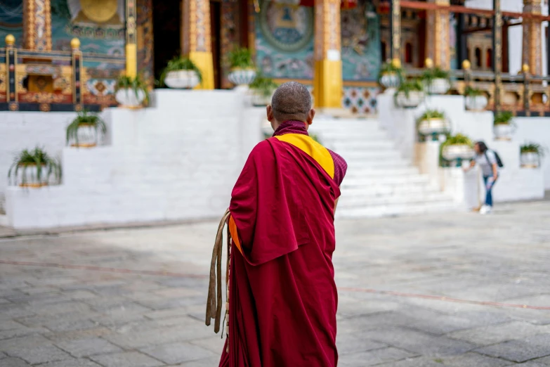 a man wearing a red and yellow robe outside