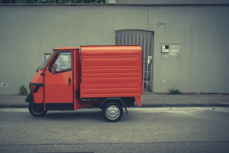 a small orange truck sitting on the side of the road