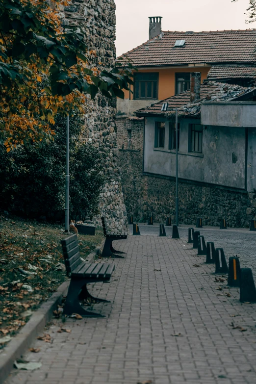 a row of wooden park benches next to a brick path