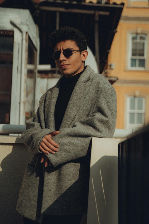 a man wearing sunglasses standing on a ledge