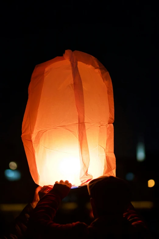 a person releasing a lite lantern into the night sky