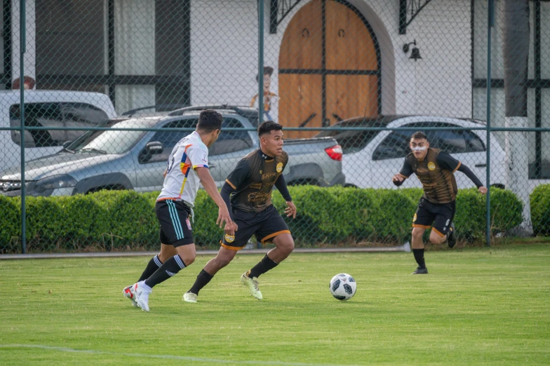 three young men playing a game of soccer in a field