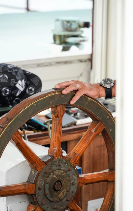 a person has their hand on the wheel of a ship