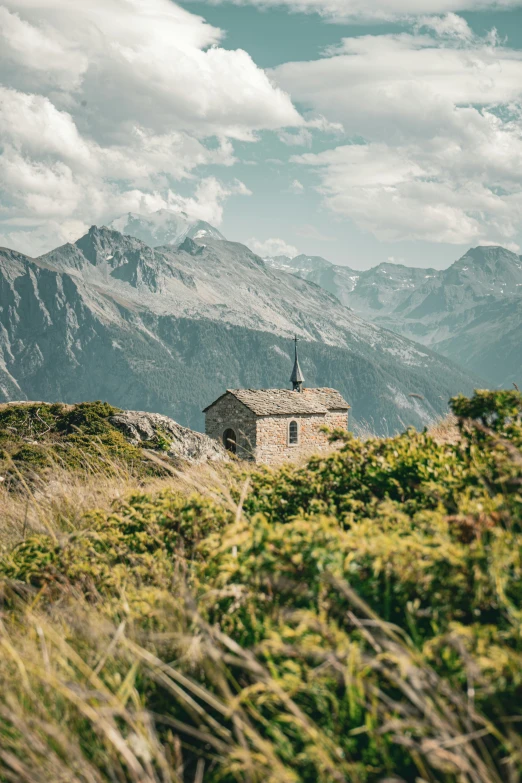 a tower sits atop a hill with mountains in the background